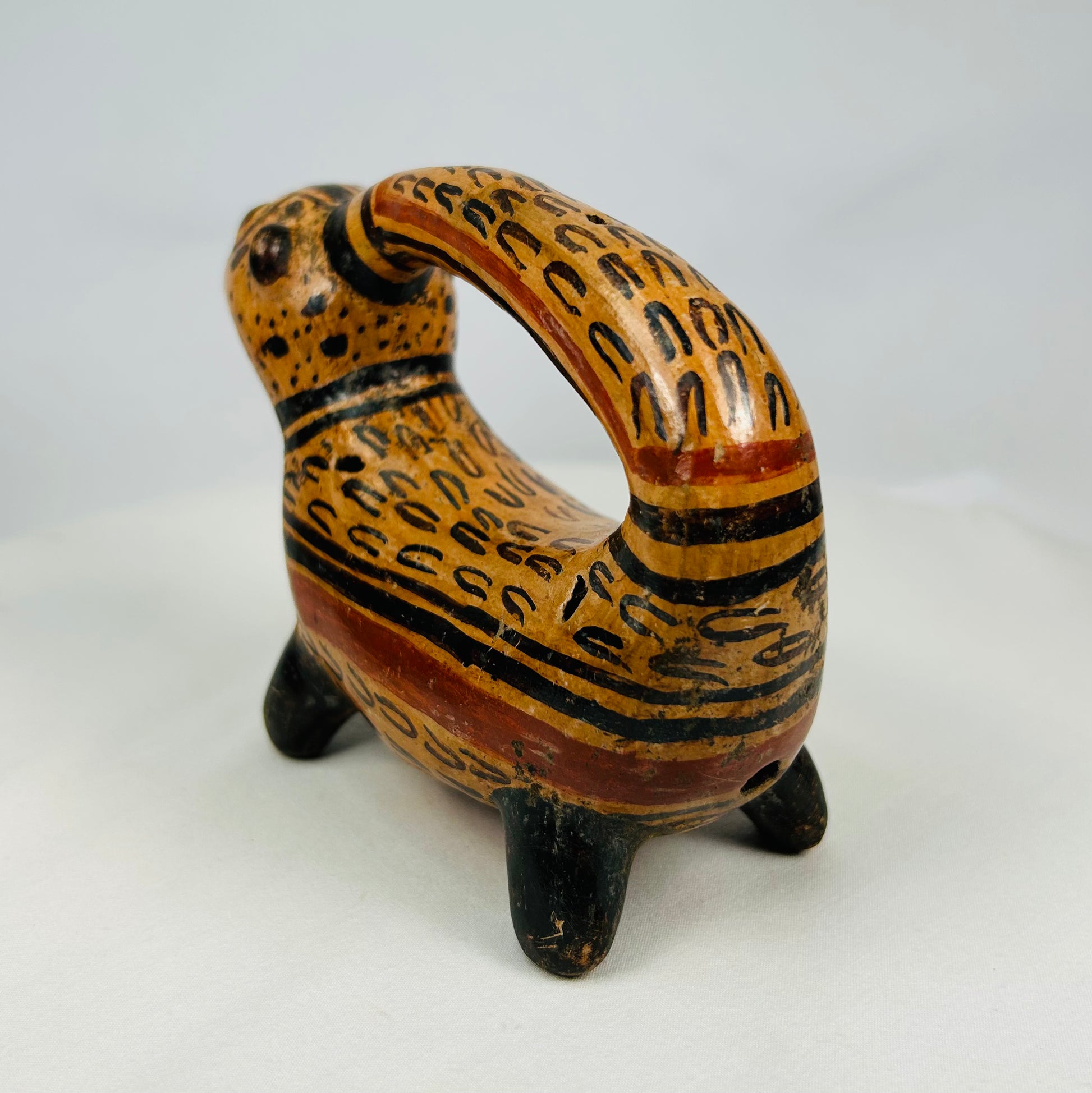 Rear angled view of Costa Rican jaguar-shaped ceremonial vessel showing arch handle and four short legs