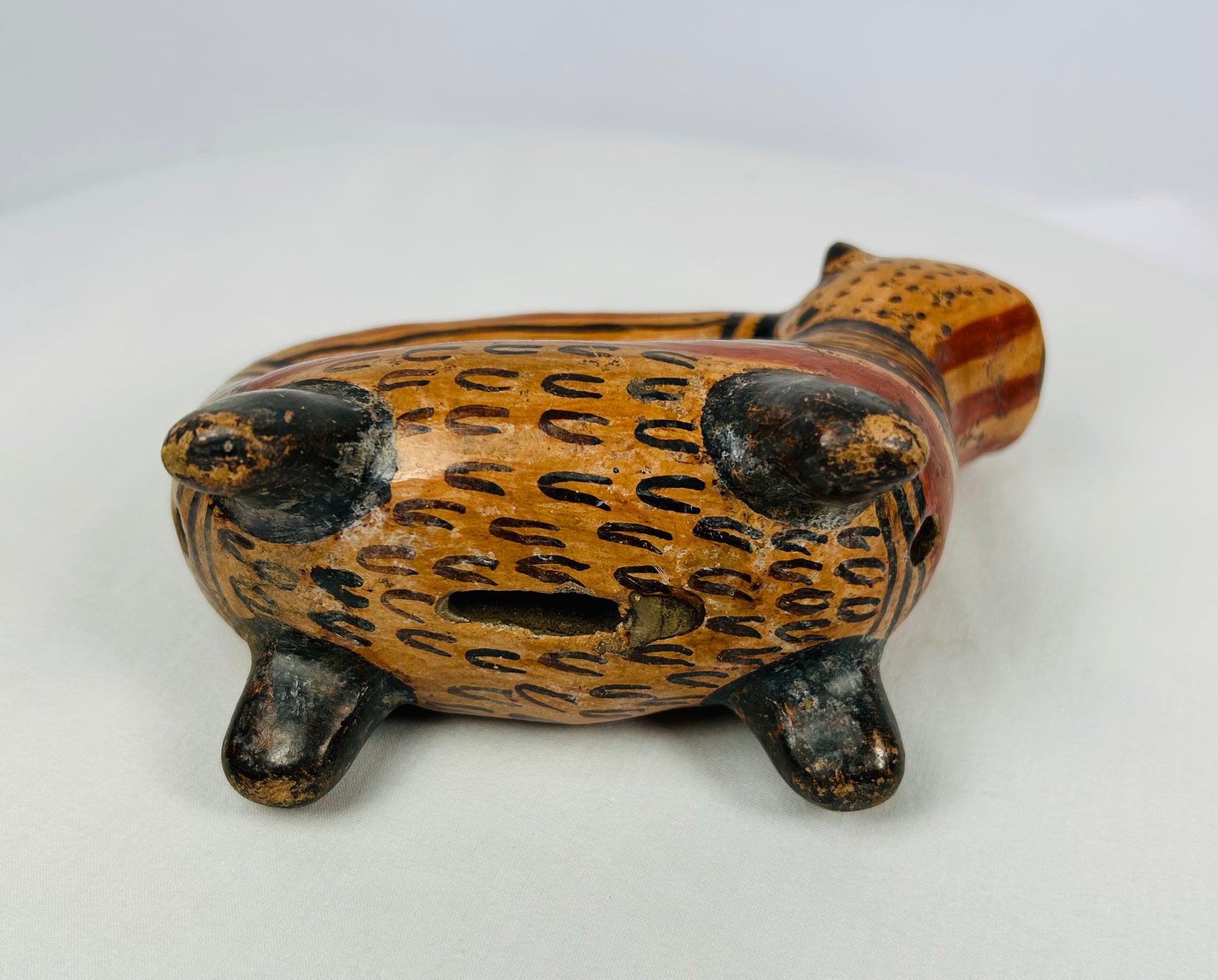 Underside view of Pre-Columbian ceramic rattle vessel showing vent aperture and feline form, Nicoya region