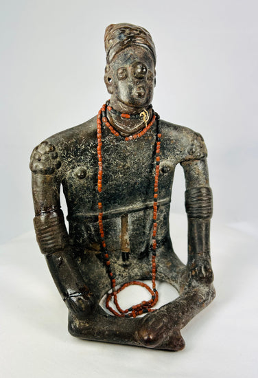 Frontal view of seated Nayarit terracotta effigy with red bead necklaces and elaborate arm bands.
