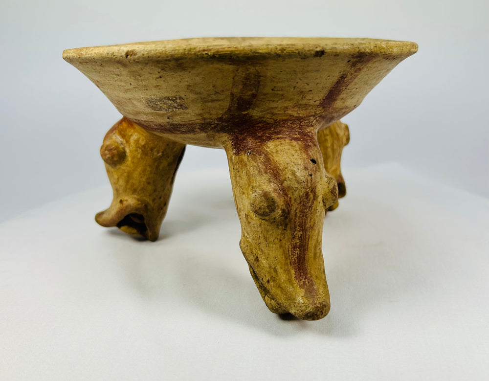 Side view of Pre-Columbian tripod bowl showing modeled zoomorphic legs and worn ochre surface