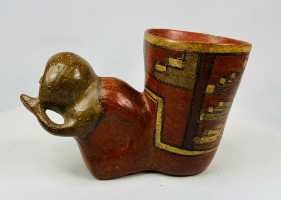 Side angle of ancient ceramic vessel with human head and red slip body decorated with stepped motifs