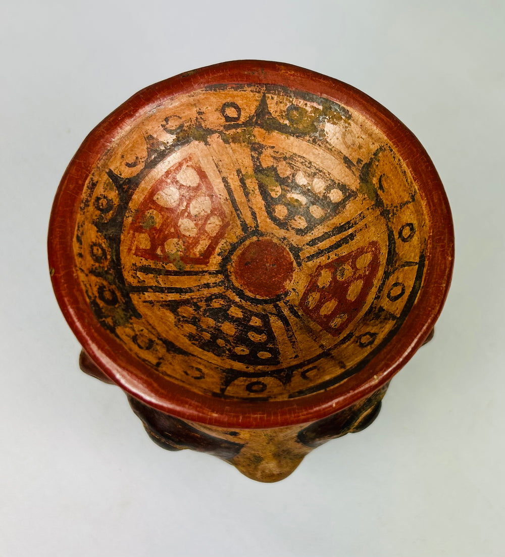 Overhead view of ancient human-headed vessel showing interior painted rim with red and black patterns