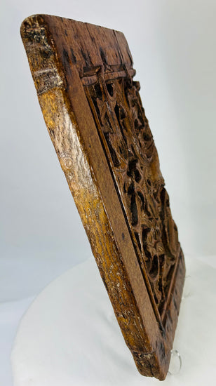 Angle of Gothic oak panel emphasizing interlaced vine and foliage carvings with shadowed recesses.