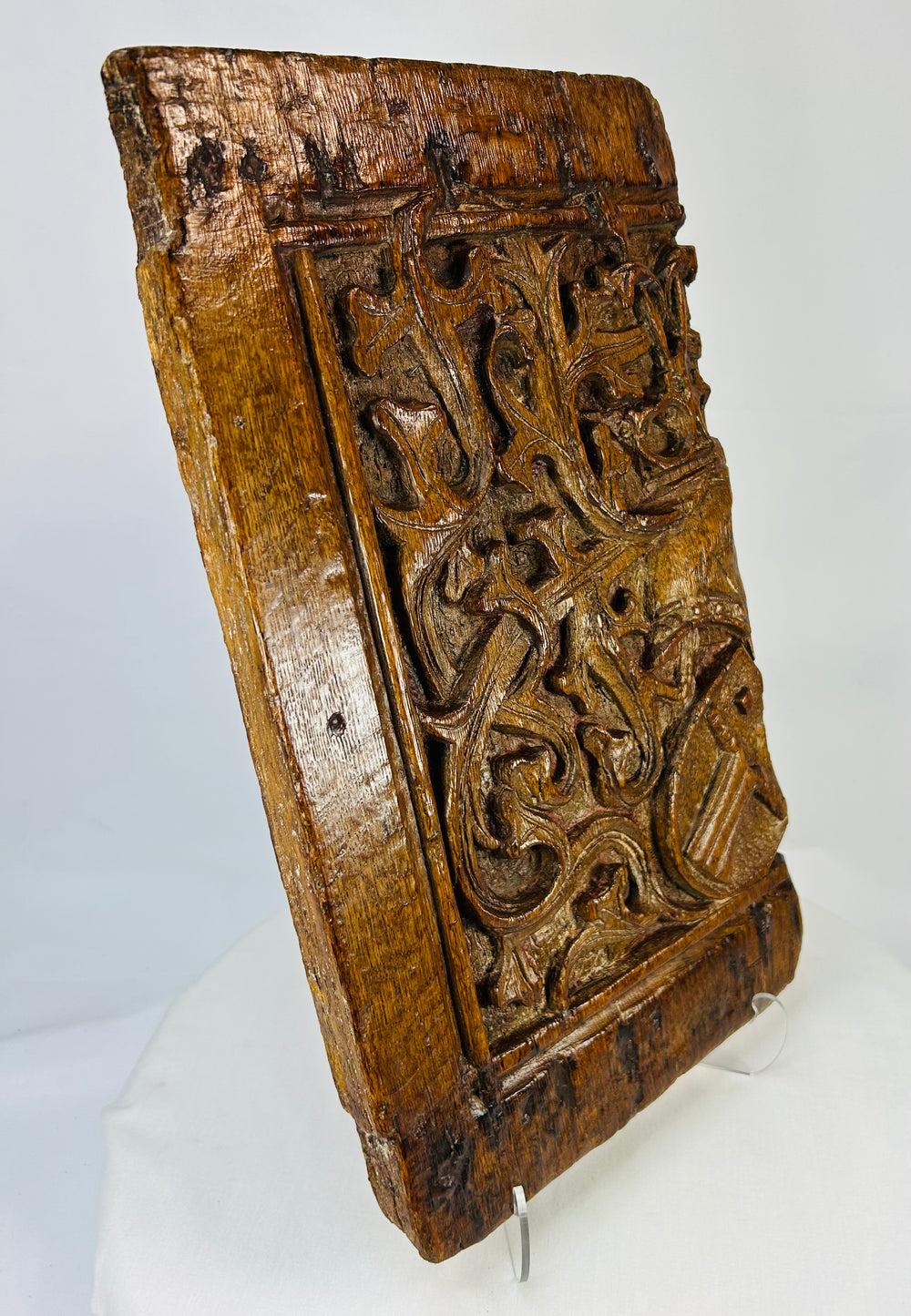 Angled perspective of Gothic oak relief panel highlighting deep carving and vine motifs in warm aged patina.
