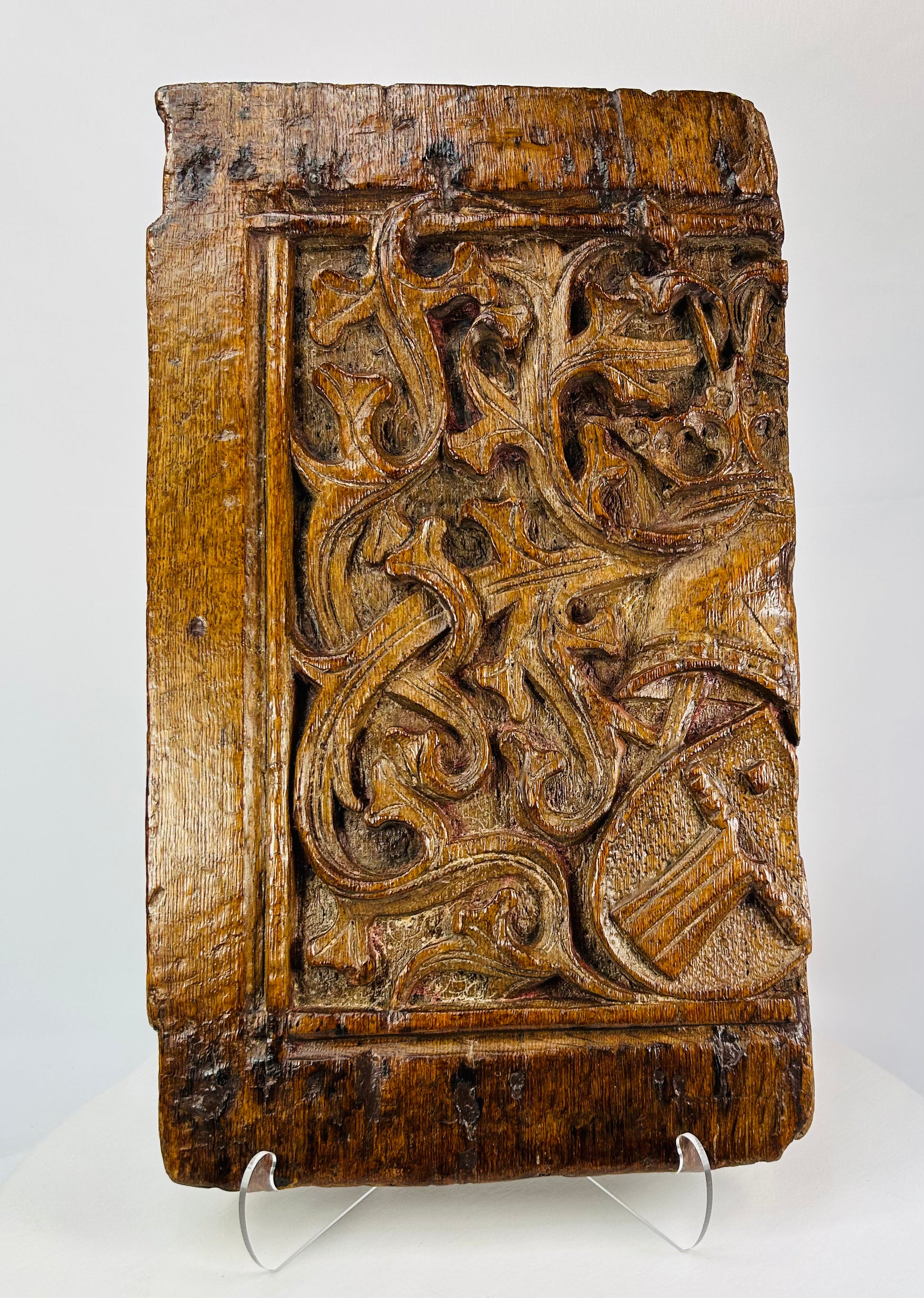 Close-up of central heraldic shield on antique oak panel displaying raised chevron design and chisel detail.