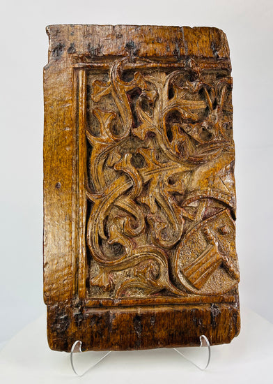 Close-up of central heraldic shield on antique oak panel displaying raised chevron design and chisel detail.