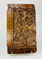 Close-up of central heraldic shield on antique oak panel displaying raised chevron design and chisel detail.