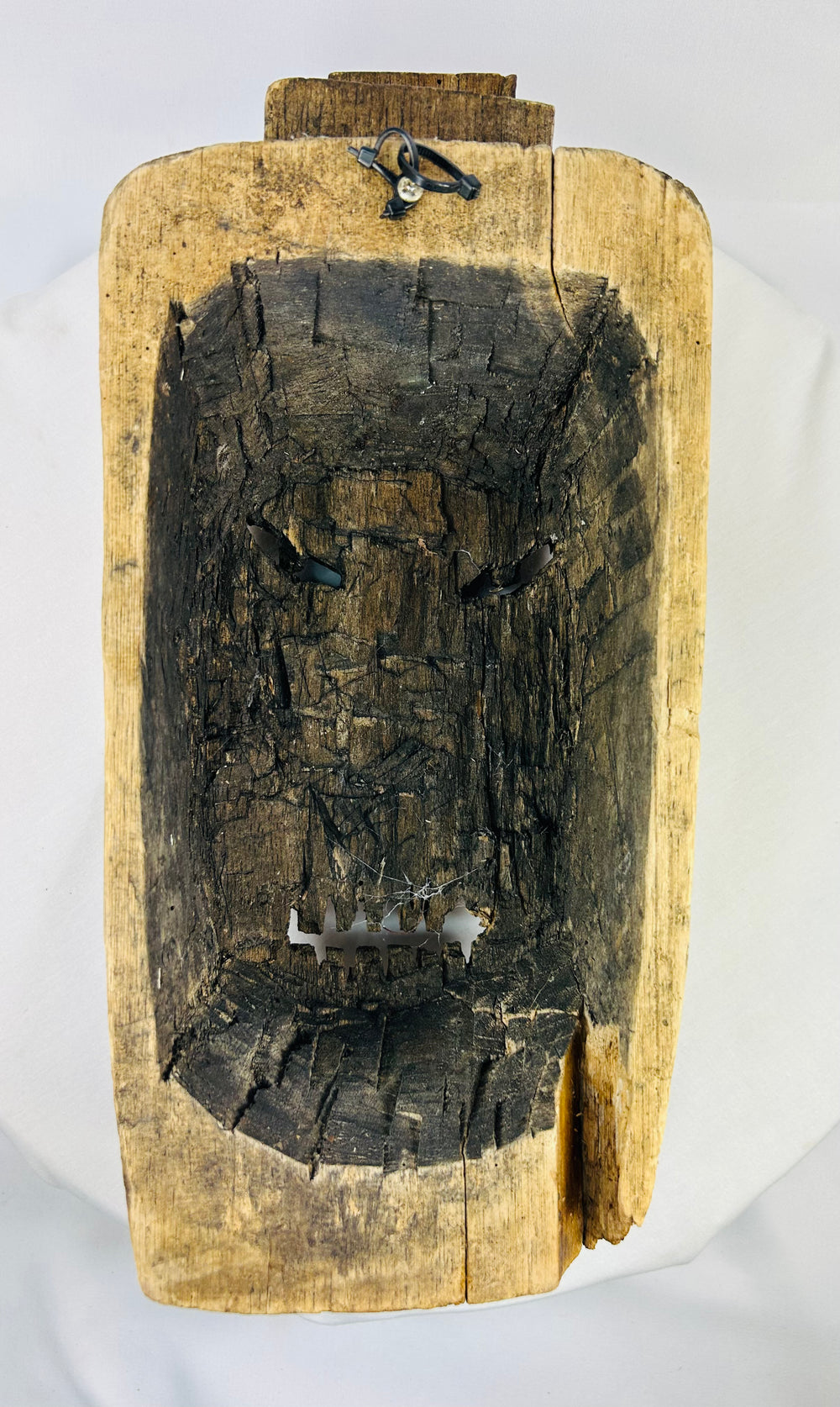 Reverse view of carved mask showing hollowed interior and attachment marks from traditional use or mounting.