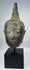 Bronze Buddha head with tightly modeled curls and elongated facial features