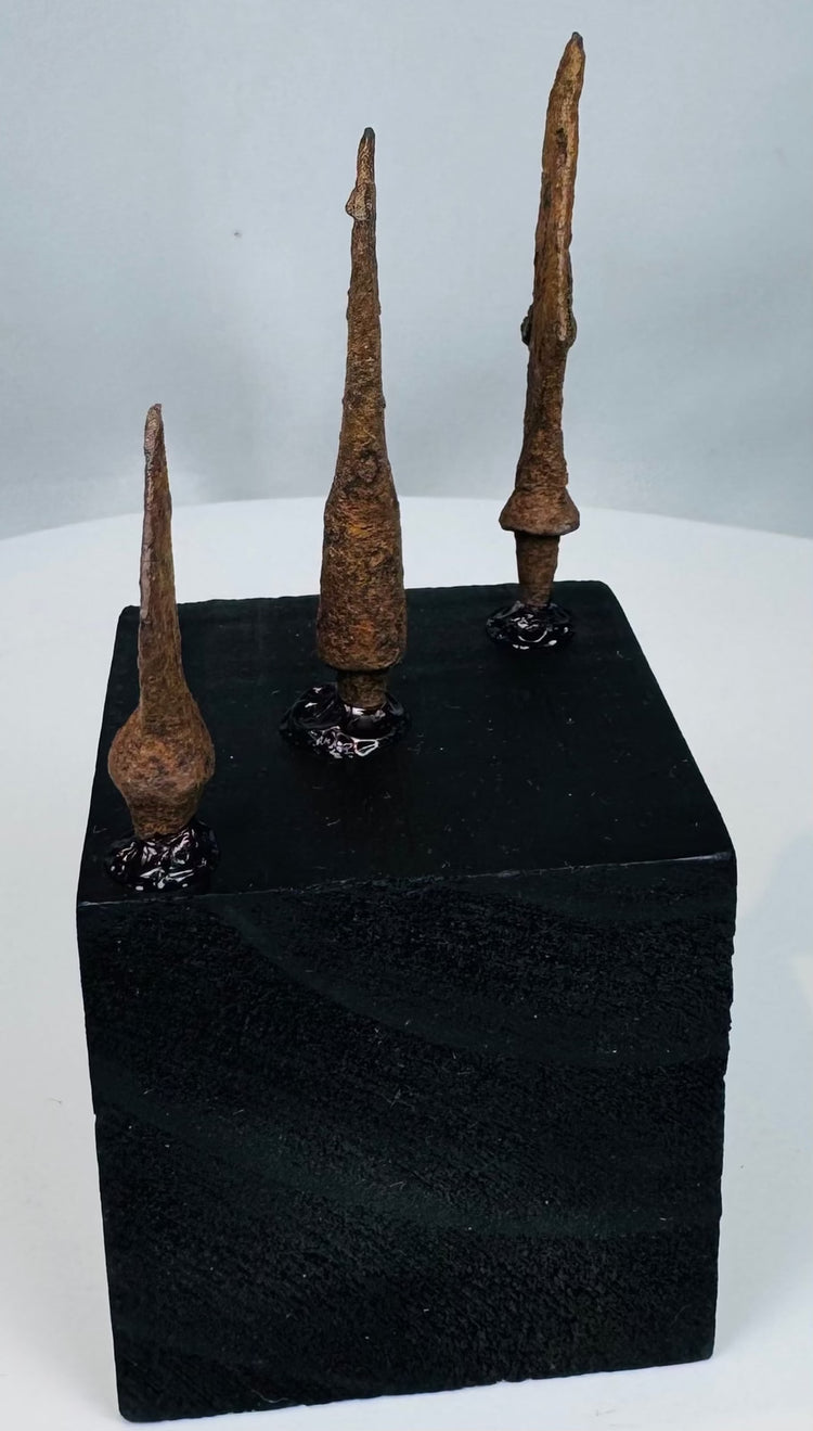 Three ancient iron spearheads mounted on a black wooden block