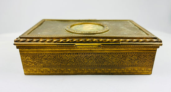Antique gold decorative box showing engraved floral patterns along the side on a white background.