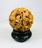 Chinese antique puzzle ball featuring intricate dragon carving on a black wooden stand against a white background.