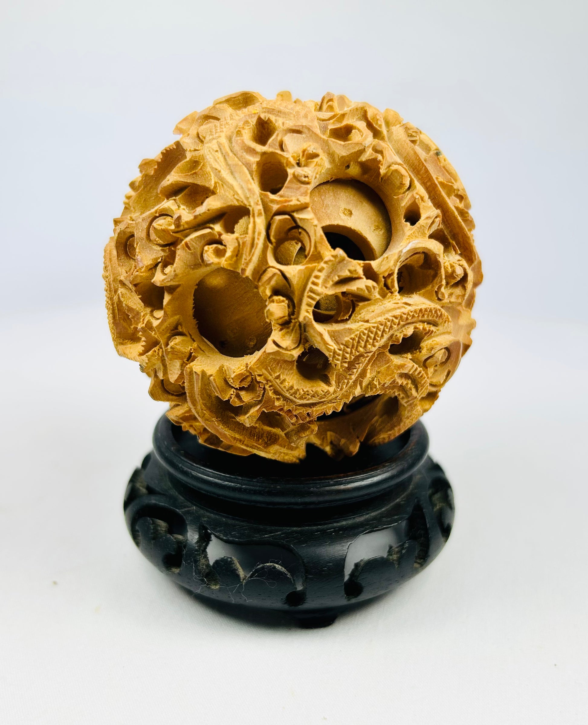 Late Qing carved multi-layer puzzle sphere with dragon designs displayed on a black stand against a white background.