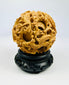 Late Qing carved multi-layer puzzle sphere with dragon designs displayed on a black stand against a white background.