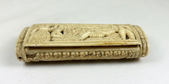 Side view of a Napoleonic POW carved bone snuff box showing relief carving and the hinged lid on a white background.