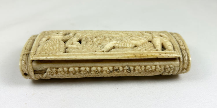 Side view of a Napoleonic POW carved bone snuff box showing relief carving and the hinged lid on a white background.