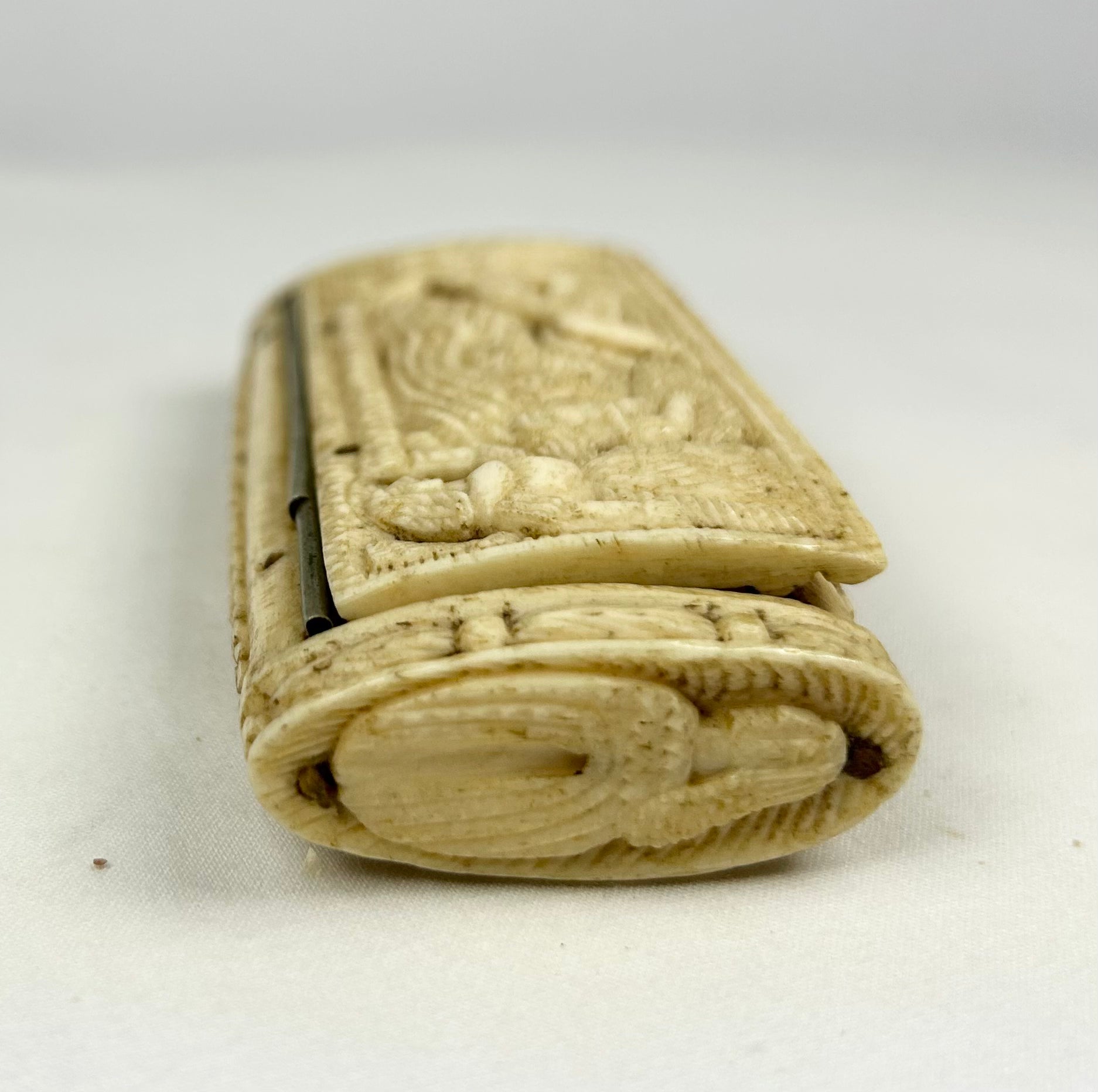 Carved bone snuff box end showing detailed woven and knotted relief patterns, attributed to Napoleonic POW craftsmanship.