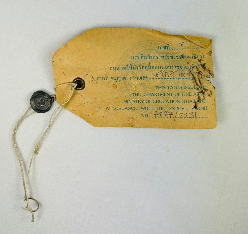 Thai Ministry of Fine Arts export permit tag attached to antique Guanyin bronze statue, verifying legal cultural artifact export.