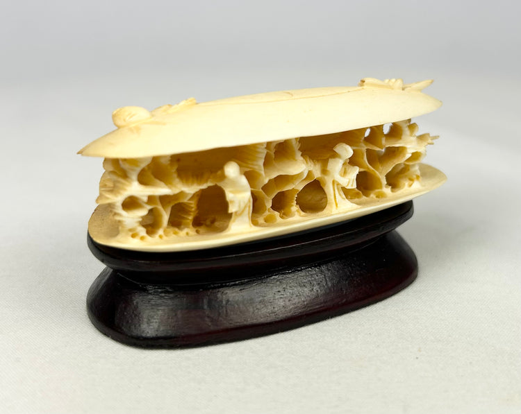 Side perspective of the Chinese carved bone clam shell miniature with detailed interior figures and natural bone coloration.”