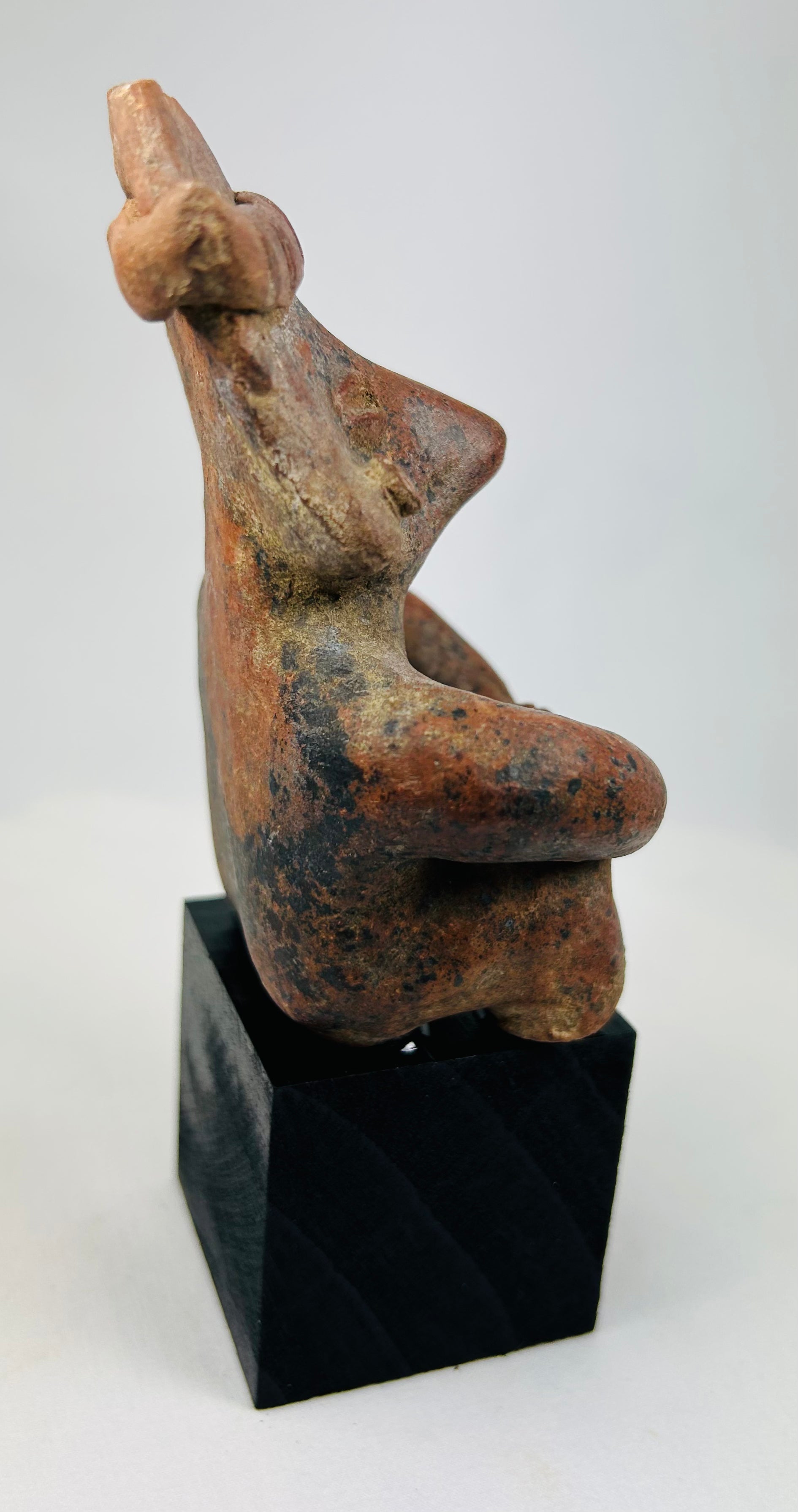 Angled shot of Nayarit seated figure highlighting textured surface and patina.