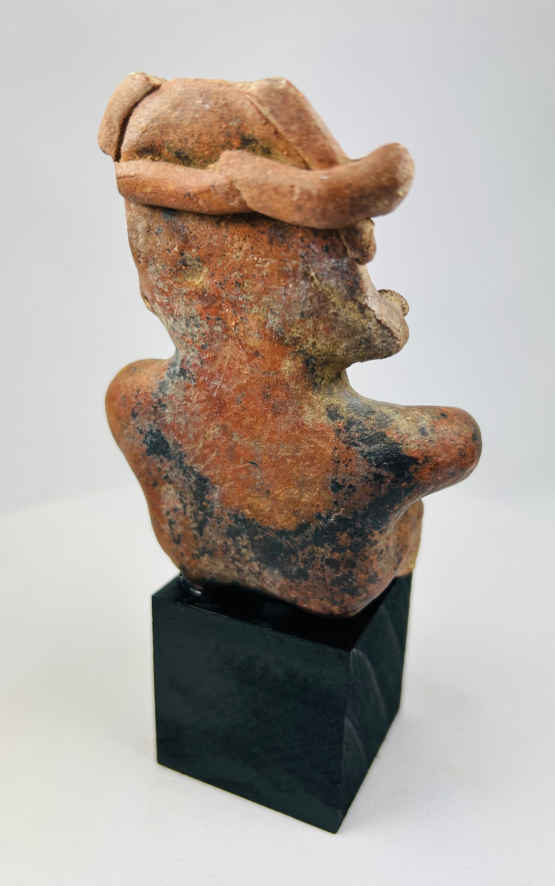 Rear view of Pre-Columbian Nayarit figure showing headdress and back surface wear.