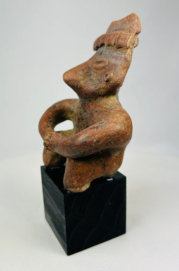 Oblique view of Nayarit seated terracotta sculpture with mineral deposits visible.