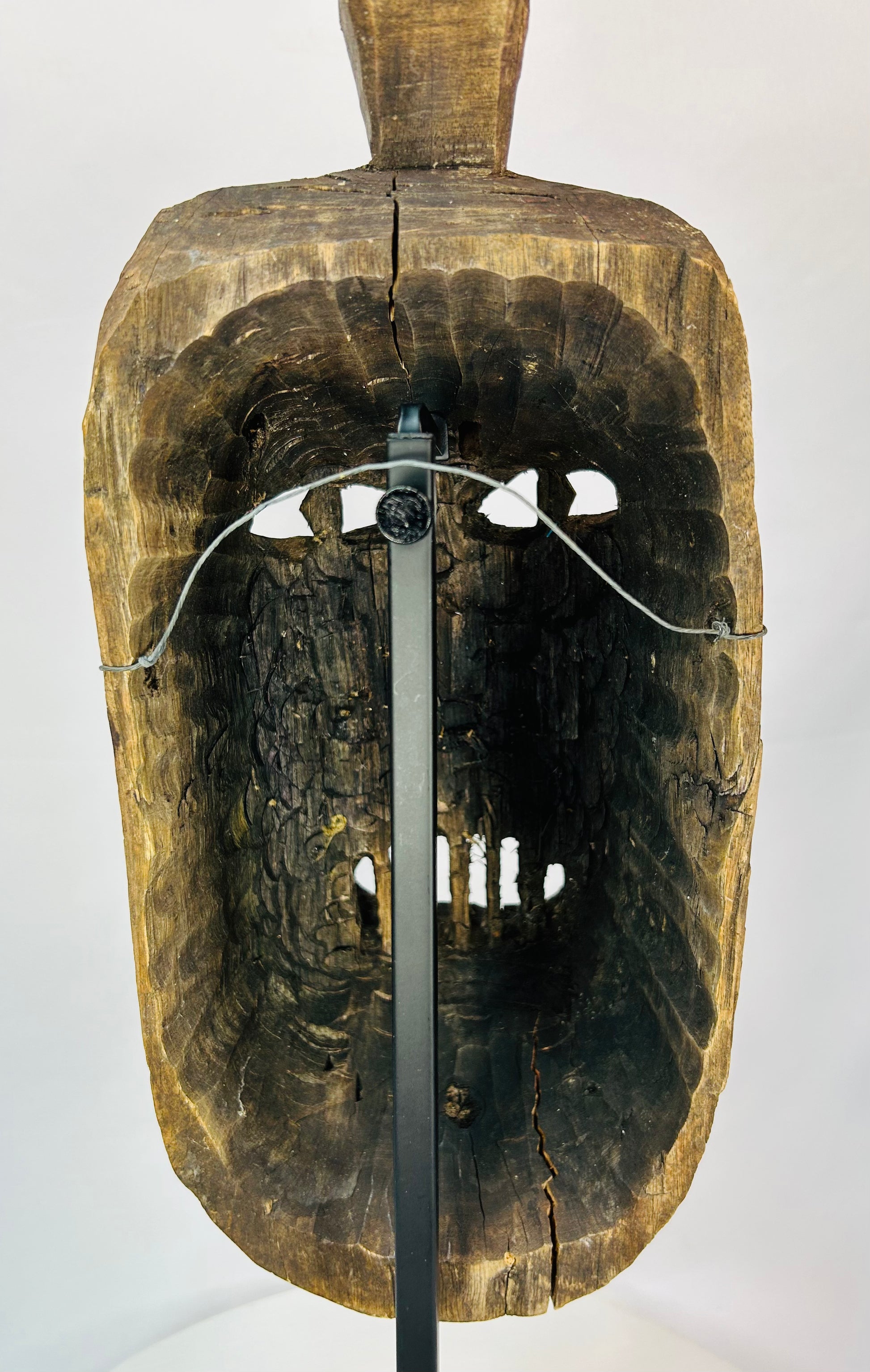 Rear view of a ceremonial wooden mask revealing tool marks and structural carving.