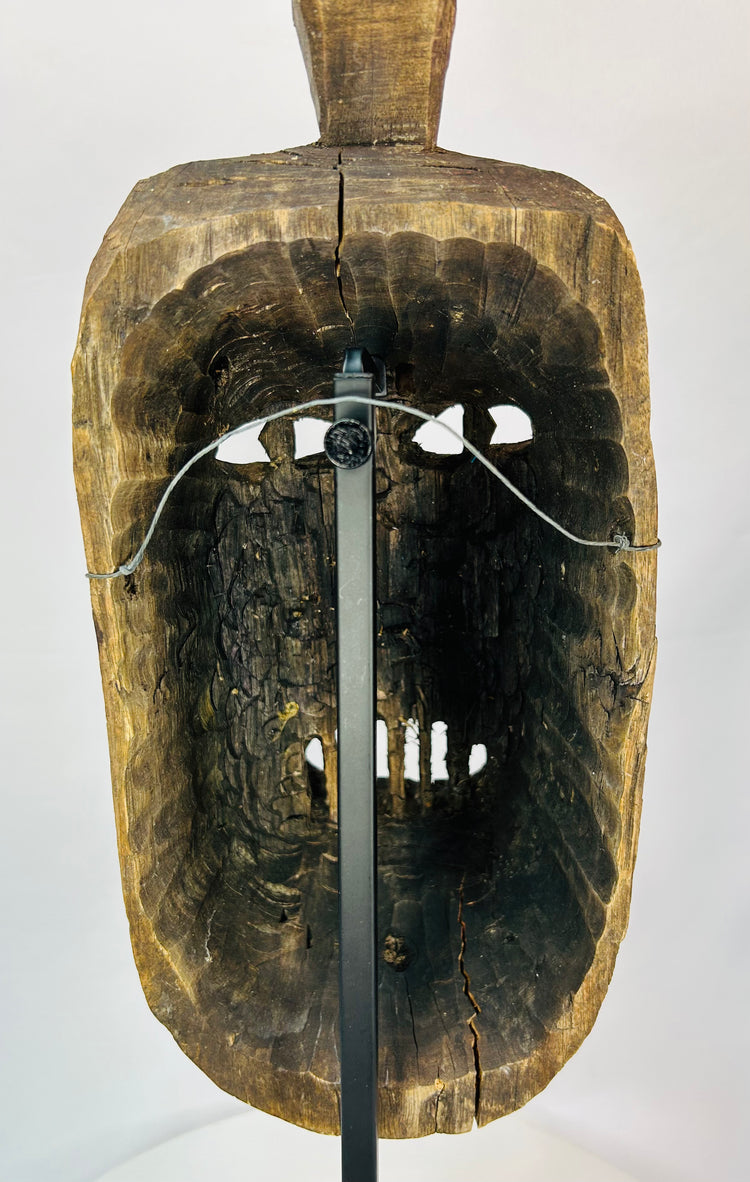 Rear view of a ceremonial wooden mask revealing tool marks and structural carving.