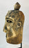 Oblique angle of a carved wooden mask revealing surface cracking and age wear.