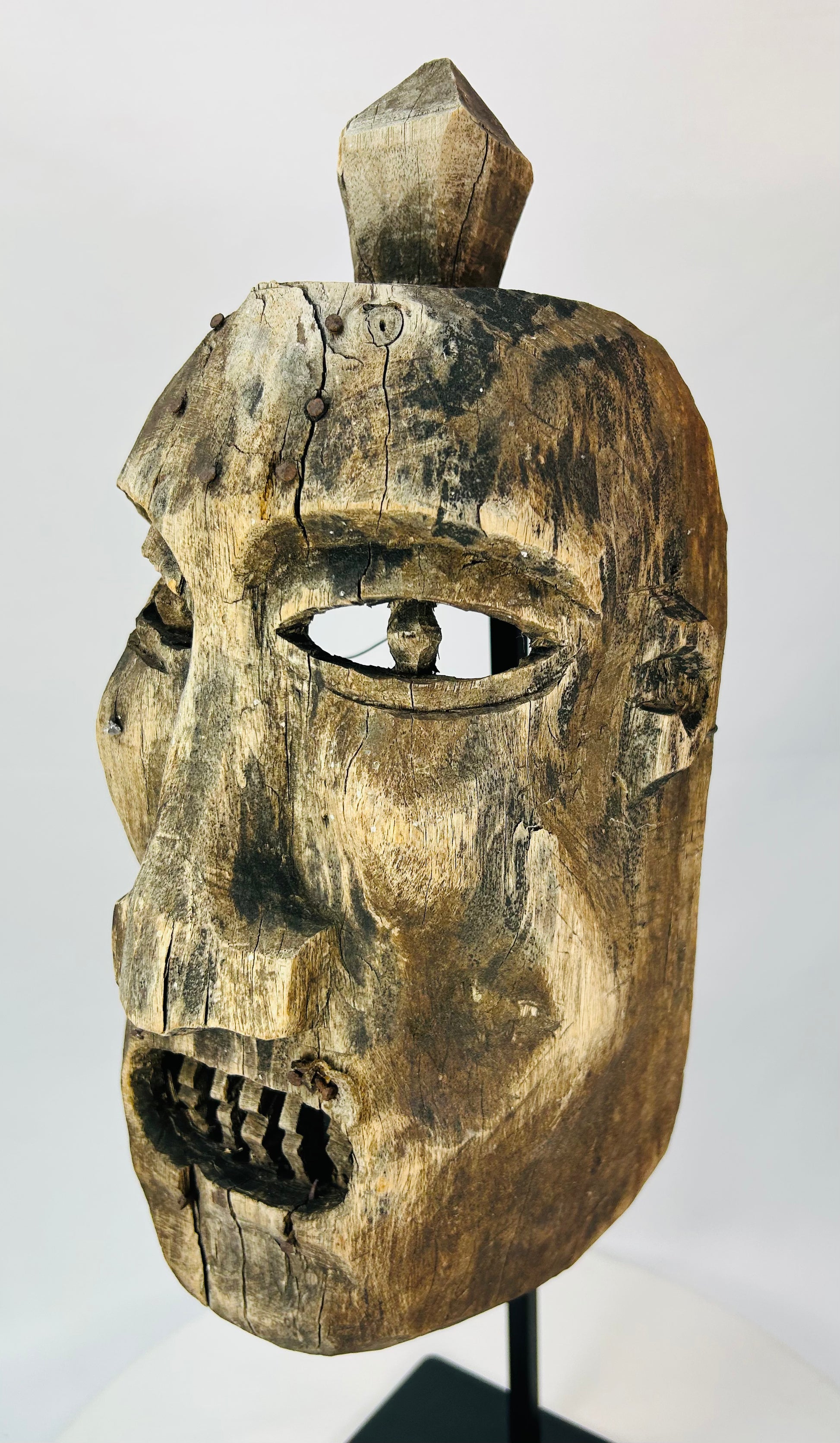 Close-up of the mask’s eye openings showing carving marks and weathered wood grain.