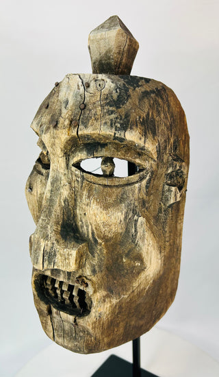 Close-up of the mask’s eye openings showing carving marks and weathered wood grain.