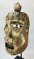 Close-up of the mask’s eye openings showing carving marks and weathered wood grain.
