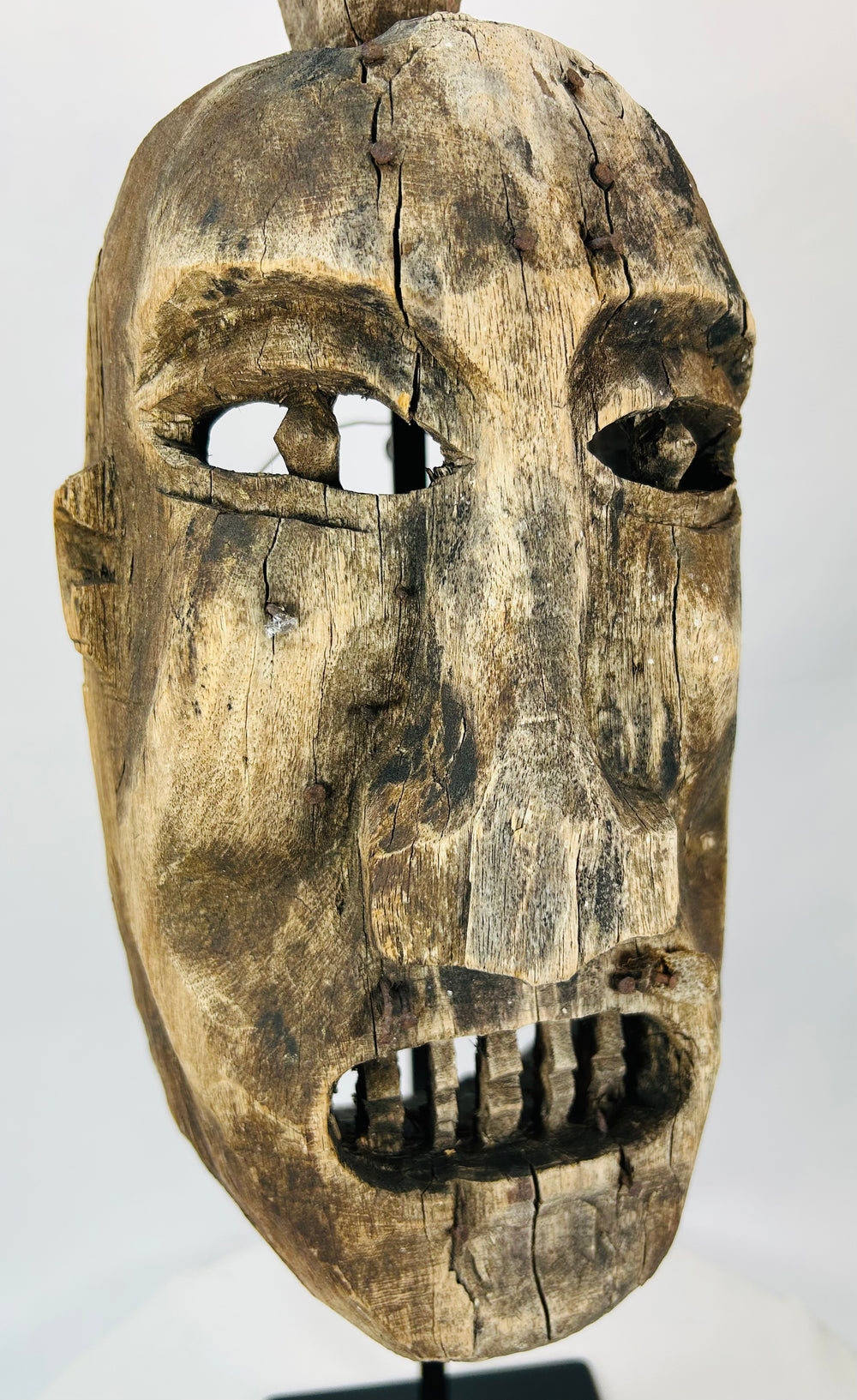 Surface texture detail of the antique wooden mask highlighting cracks and coloration.