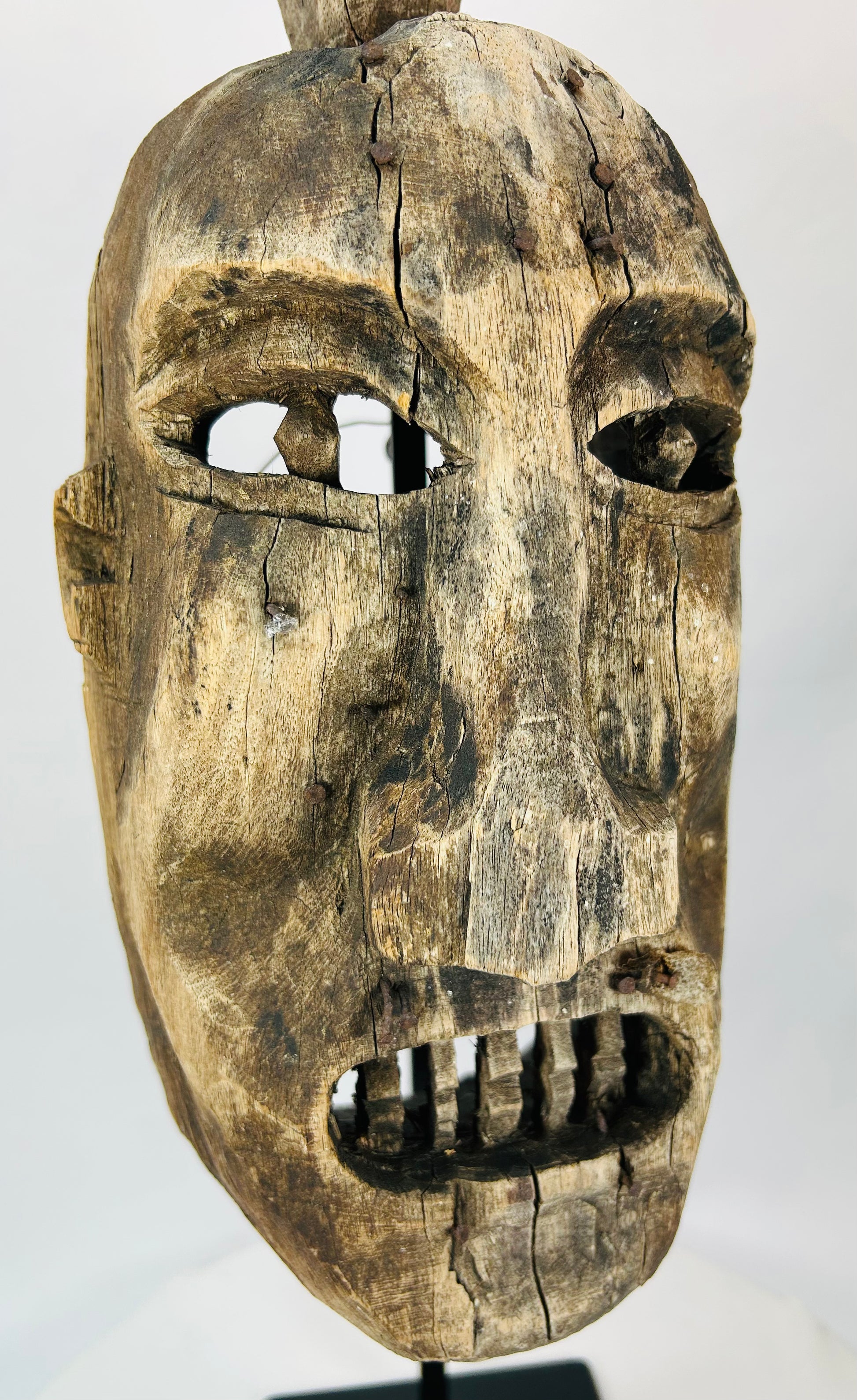 Surface texture detail of the antique wooden mask highlighting cracks and coloration.