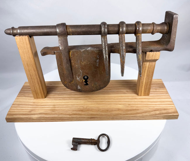Hand-forged wrought-iron door lock assembly displayed on a custom wooden stand