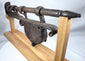 Rear angle of a large hand-forged gate lock mounted on a custom wooden stand