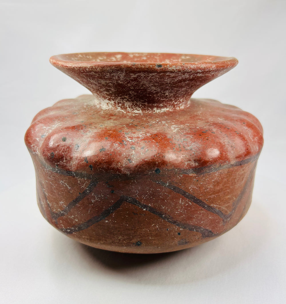 Side view of a Pre-Columbian terracotta vessel with zig-zag geometric paint and scalloped shoulder