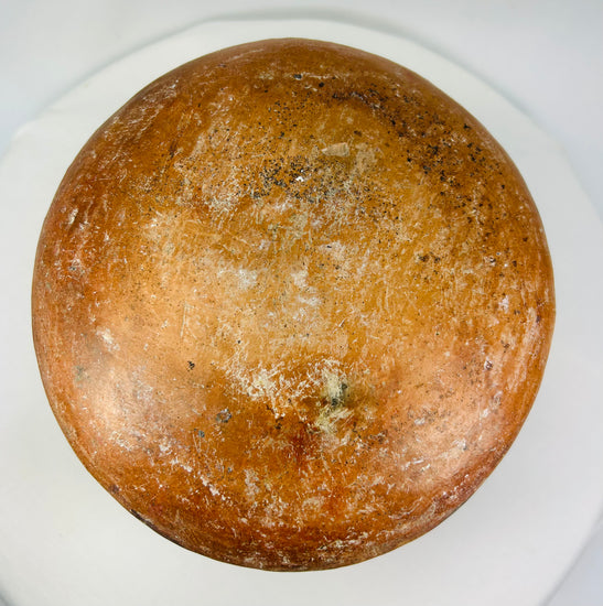 Underside of a Pre-Columbian ceramic vessel showing natural wear and mineral deposits on a rounded terracotta base.
