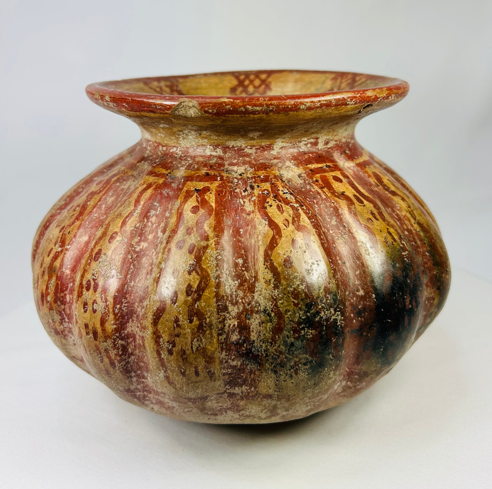 Side view of a Pre-Columbian Moche-style ceramic vessel showing red and gold streaked painted surface.