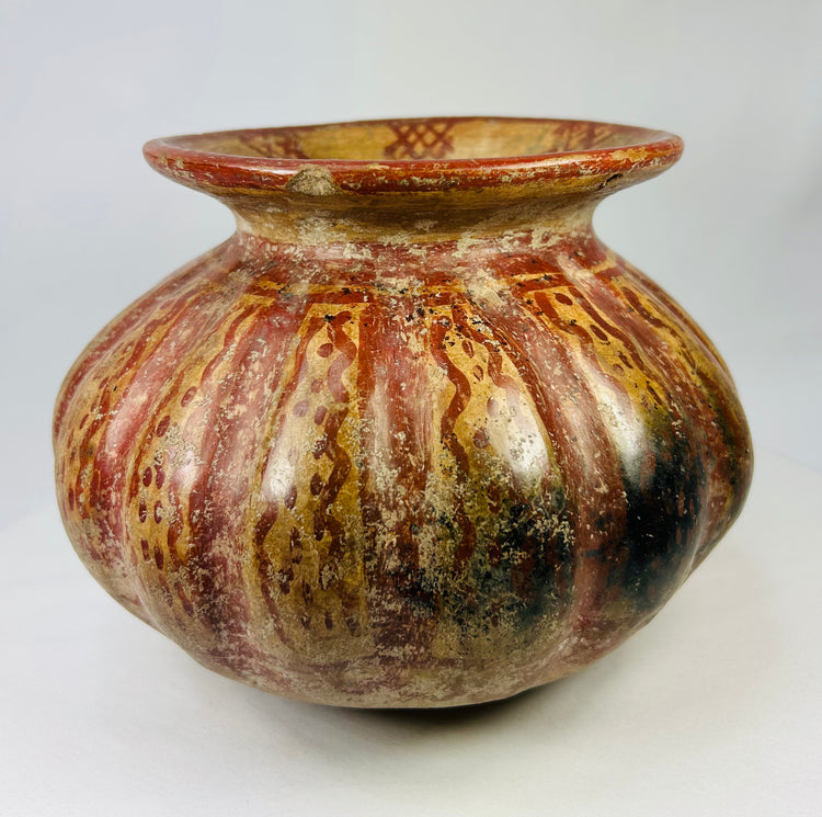 Side view of a Pre-Columbian Moche-style ceramic vessel showing red and gold streaked painted surface.