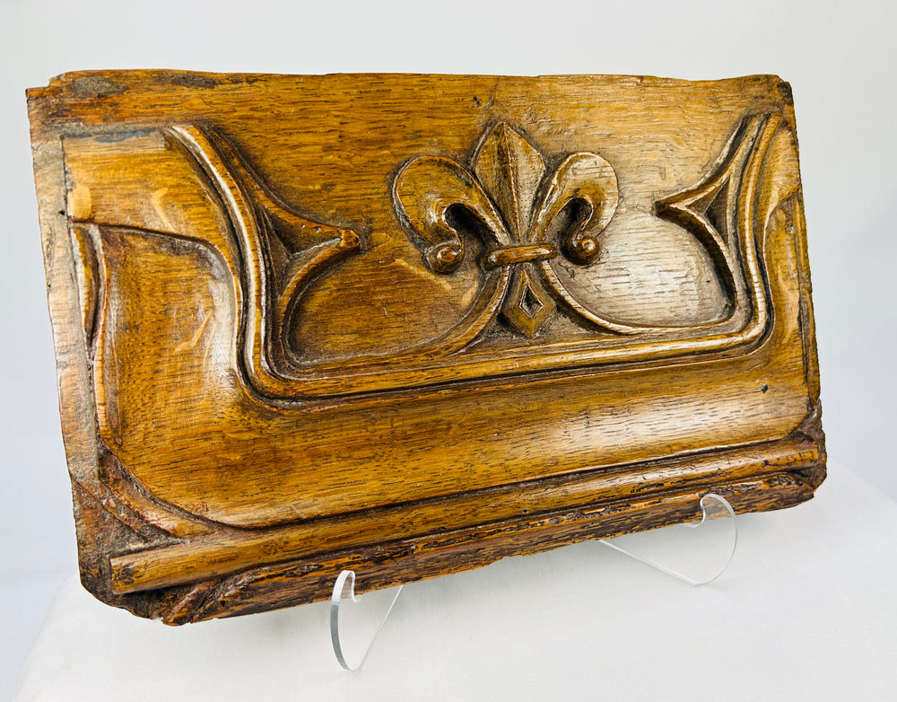 Angled view of antique Gothic oak relief panel showing carved fleur-de-lis design