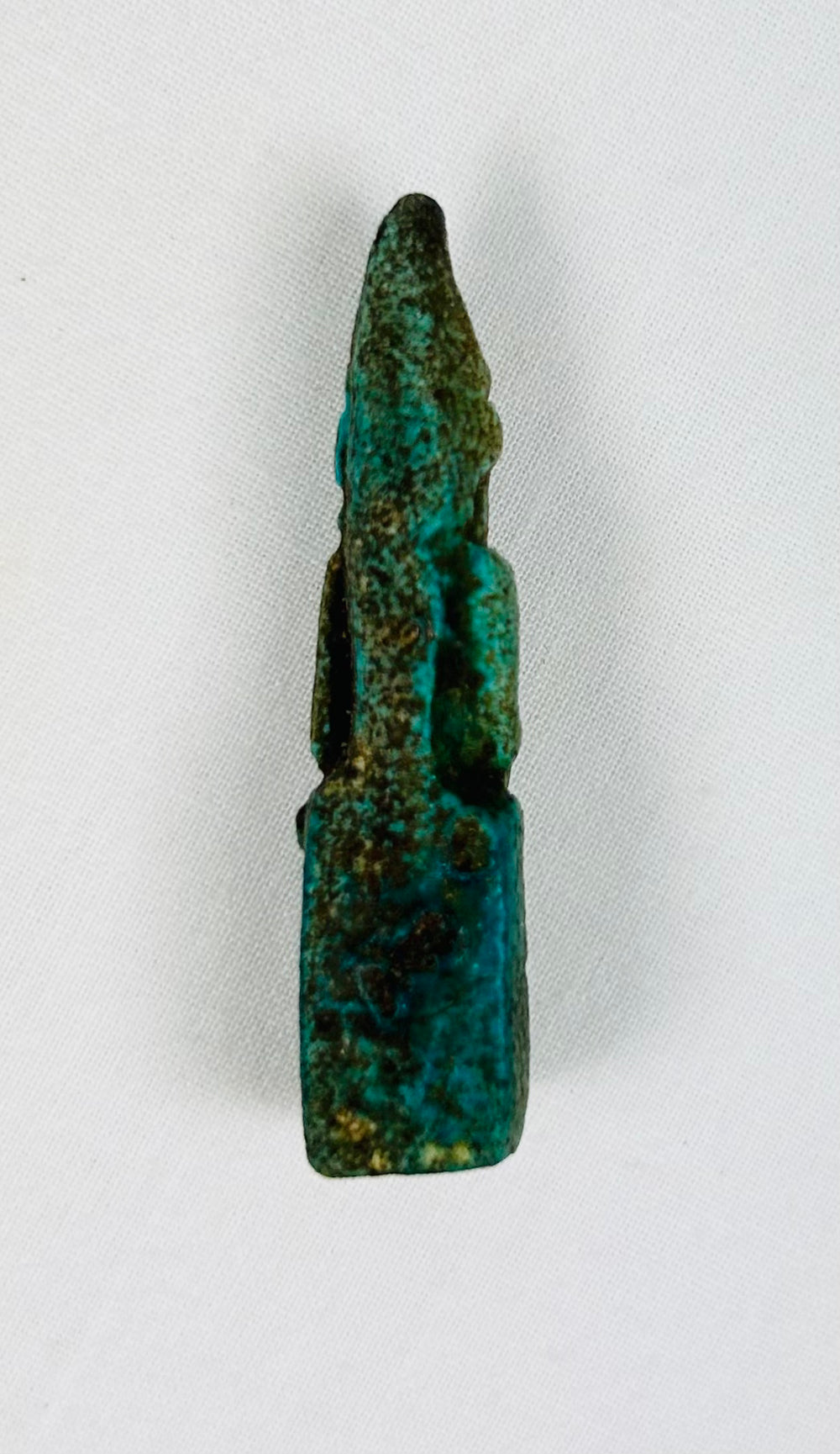 Back view of small seated Egyptian goddess figurine with smooth surface wear.