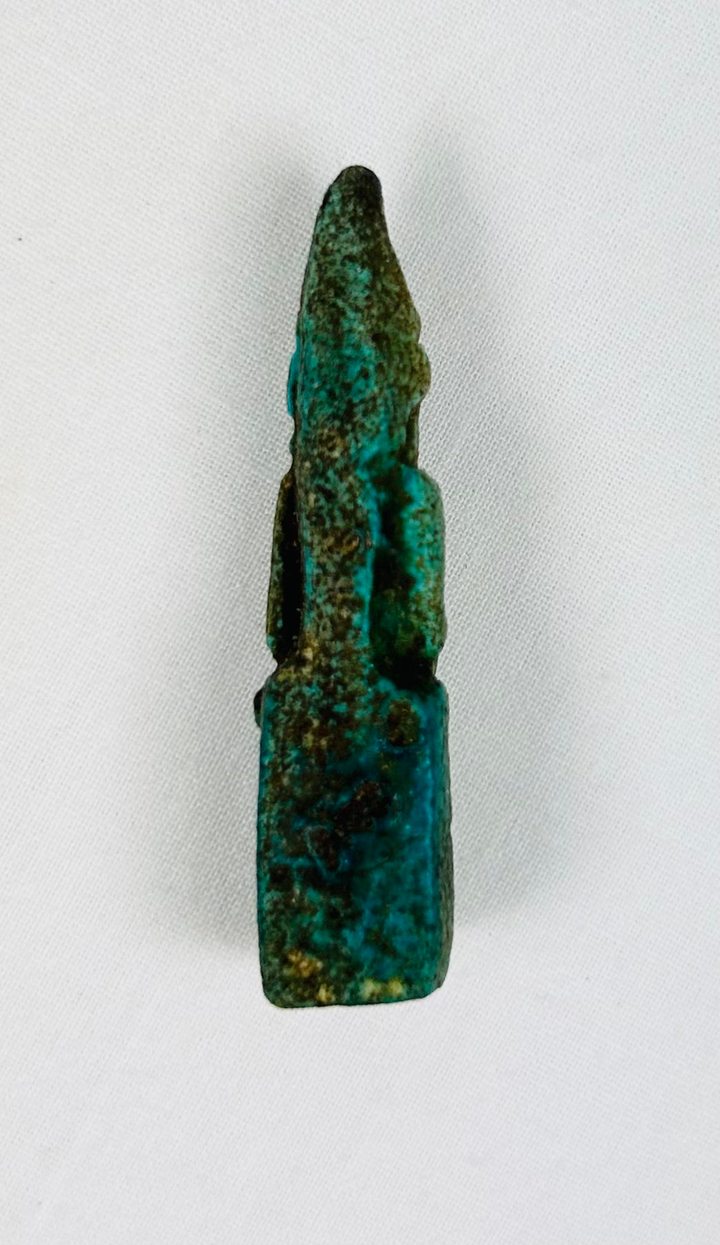 Back view of small seated Egyptian goddess figurine with smooth surface wear.