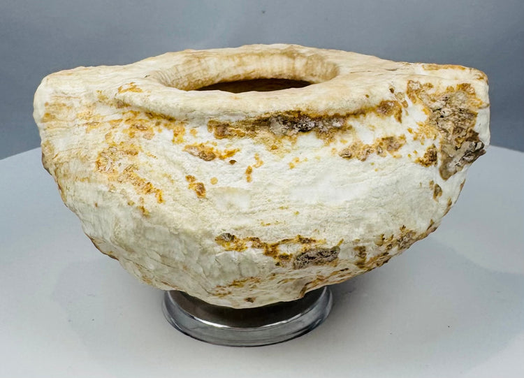 Ancient white stone vessel showing cream, ochre and brown deposits