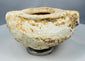 Ancient white stone vessel showing cream, ochre and brown deposits