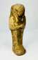Late Period Egyptian ushabti carved in sandstone photographed upright.