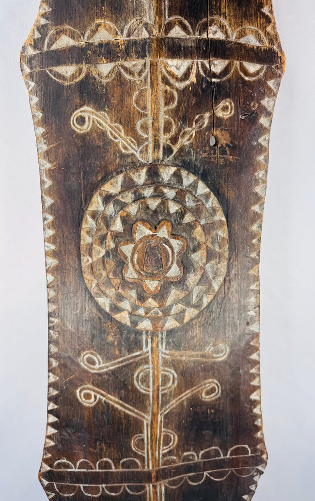 Lower section of a carved ceremonial shield with geometric borders and rounded point