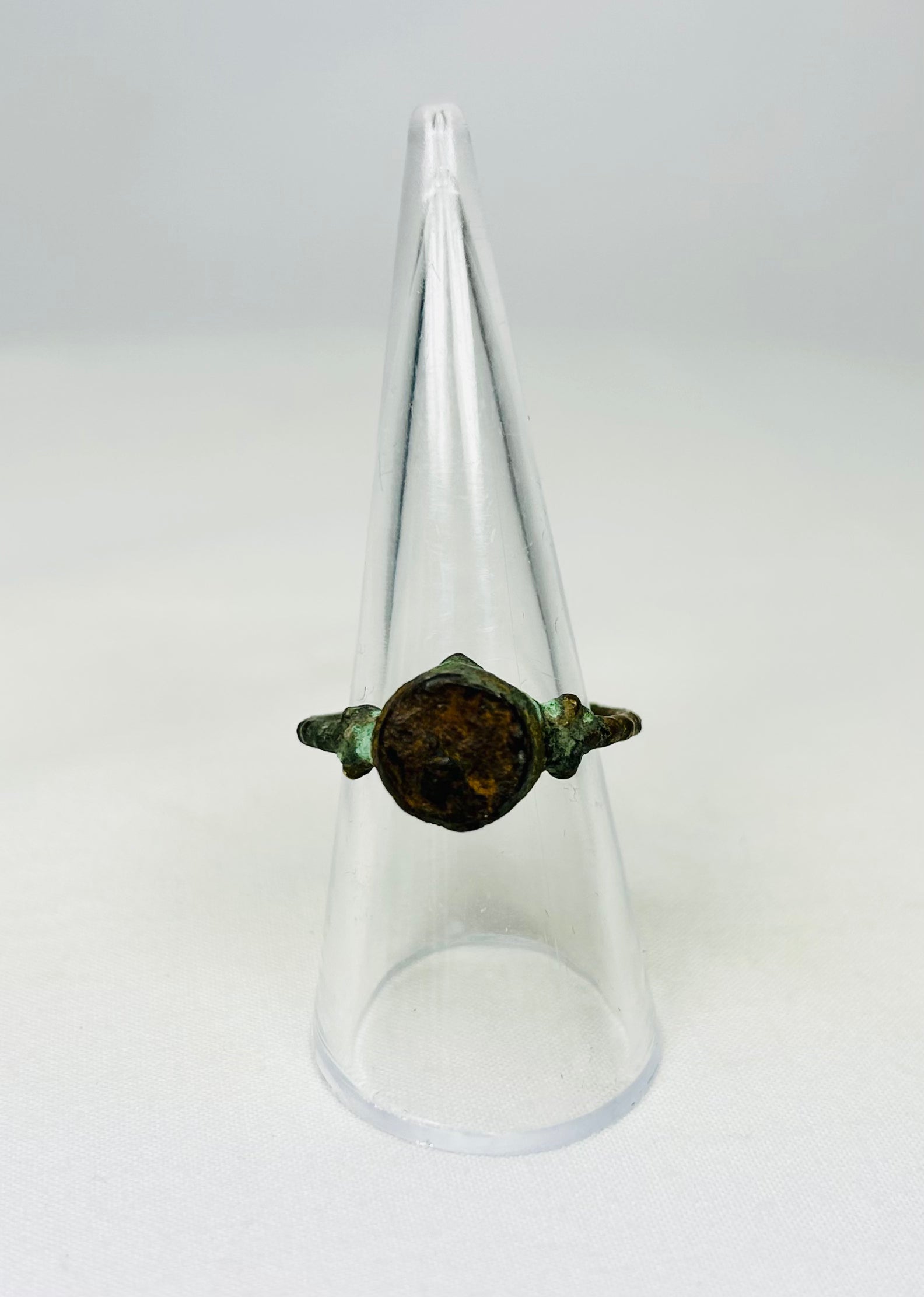 Corroded bronze ring from antiquity shown against a white background