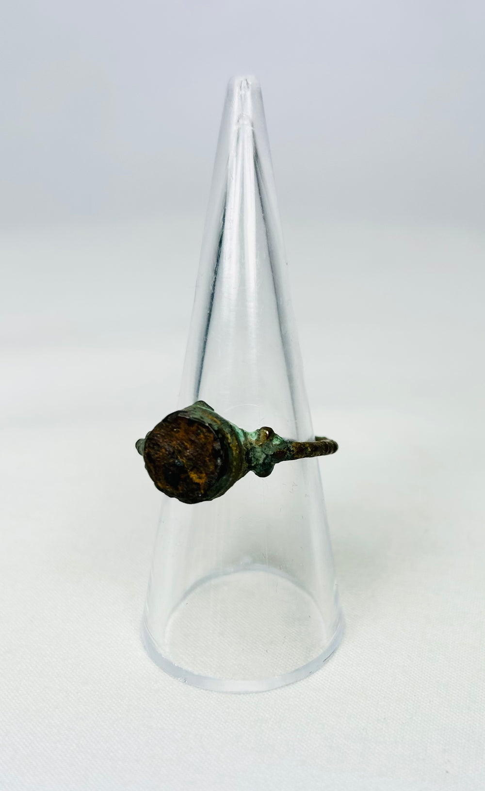 Ancient bronze signet ring resting on a black museum-style pedestal