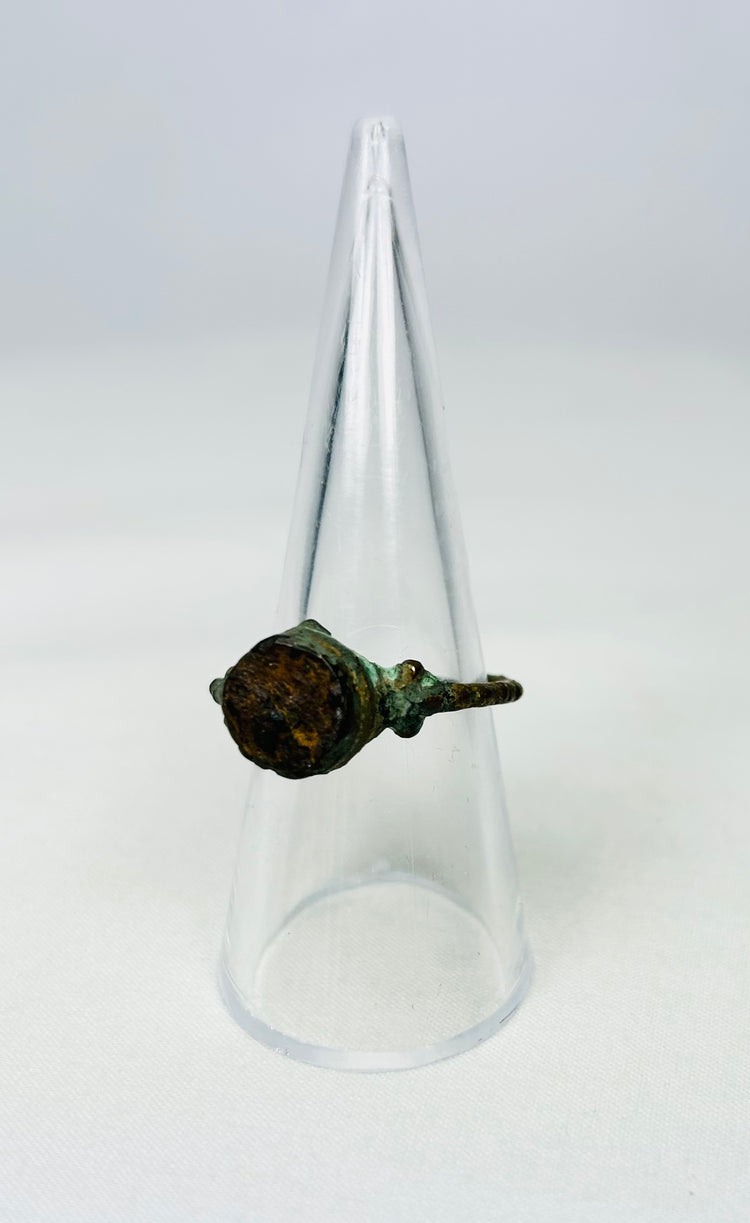 Ancient bronze signet ring resting on a black museum-style pedestal